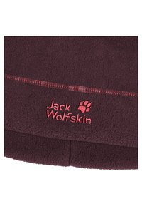 Tessuto in pile borgogna con cuciture rosse in contrasto. Presenta il logo "Jack Wolfskin" e un'impronta di zampa ricamati nella parte inferiore.