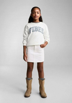 Vit sweatshirt med "VIBES" i blå bokstäver, kombinerad med en vit denimkjol och bruna cowboystövlar med gråa manschetter. Slät textur genom hela.