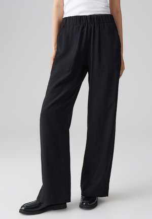 Black, high-waisted, wide-leg pants made from a smooth, lightweight material. Features two front pockets and an elastic waistband.