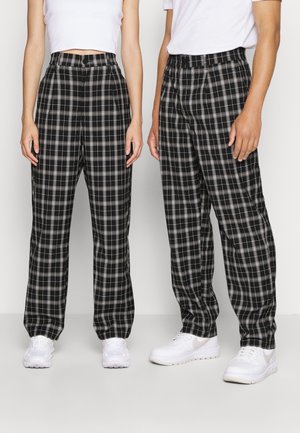Czarno-szare spodnie w kratę o luźnym kroju, z wysokim stanem, zapinane na guziki, z bocznymi kieszeniami. W połączeniu z białymi trampkami.