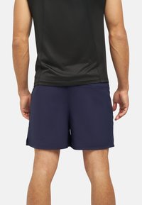 Costumi da bagno da uomo in blu navy, realizzati in tessuto leggero. Presentano spacchi laterali per la libertà di movimento e un design della vita scorrevole.