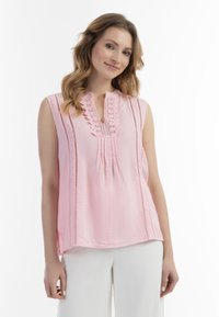 Lys pink, ærmeløs bluse med en let åben halsudskæring, dekorativ blondekant, lodrette plisseringer og subtile sideskår. Blødt, struktureret stof.