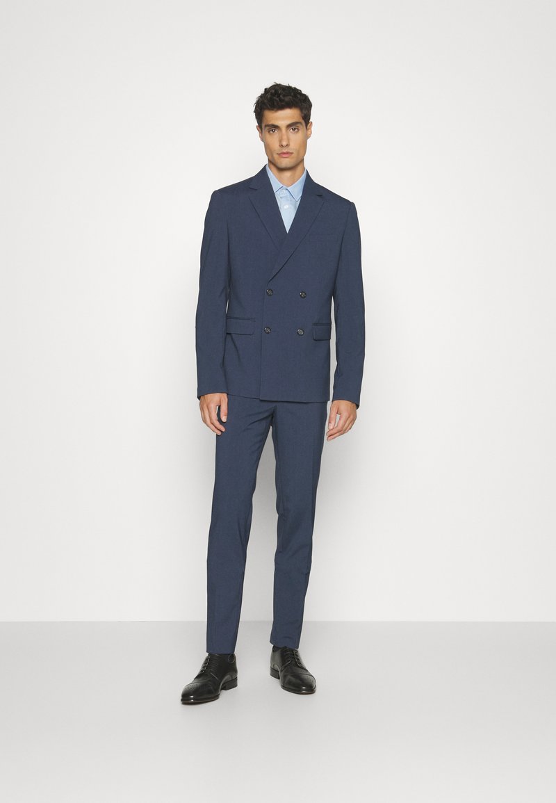 Marineblauer doppelt geknöpfter Anzug mit Reverskragen, Knopfdetails, schmaler Hose, kombiniert mit einem hellblauen Hemd und schwarzen Businessschuhen.