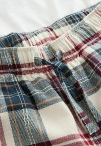 Kockované spacie šortky s bielym, modrým a červeným vzorom. Obsahujú elastický pás s šnúrkou a príjemnú textúru.