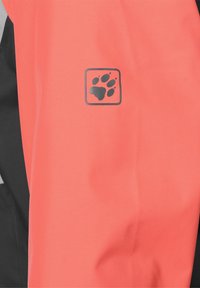 Koralowo-czarna kurtka outdoorowa z logo w kształcie łapy po lewej stronie, wykonana z trwałej, teksturowanej tkaniny.