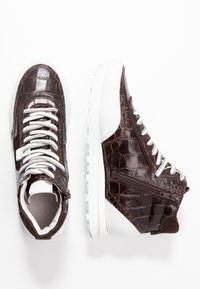 Baskets en cuir marron au motif crocodile avec semelles blanches, lacets blancs, fermeture éclair sur le côté et col rembourré, montrées en vue de dessus et en vue de côté.