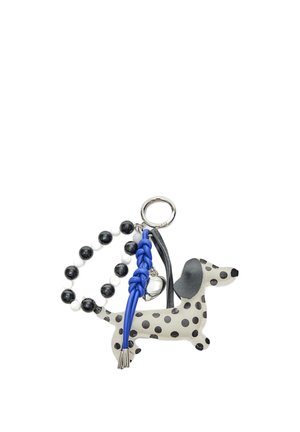 Obesek za ključe s figuro pikastega psa, črno-belo perlico v obliki zanke, pletenim modrim trakom in majhnim srebrnim zvončkom, pritrjenim na kovinski obroč.