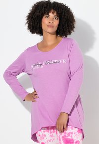 Vaalean violetti, pyöreäkauluksinen pitkähihainen paita, jossa valkoinen "Stay Positive" -teksti, yhdistetty vaaleanpunaisiin tie-dye -leggingsseihin.