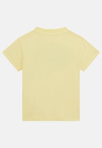 Rövid ujjú pólóing puha sárga pamutból. Klasszikus gallérral és sima hátoldallal rendelkezik. Nincsenek látható minták vagy díszítések.