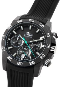 Montre bracelet chronographe noire avec un bracelet en caoutchouc texturé, un cadran noir et des accents argentés ; elle dispose de trois sous-cadrans et d'une fenêtre de date.