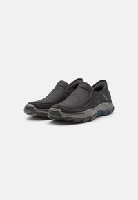 Black slip-on shoes with a textured upper, gray rubber outsole, and subtle blue accent detail. Features elastic side panels for easy wear.