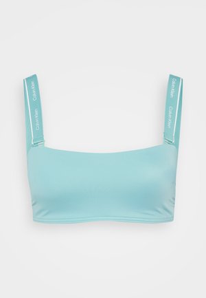 Light blue bandeau bra made from smooth, stretchy material. Features wide straps with Calvin Klein branding and contrast stitching.