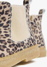 Stivaletti alla caviglia in camoscio con stampa leopardata, con pannelli laterali elasticizzati beige e suole in gomma testurizzata, caratterizzati da cuciture a vista e forma arrotondata.