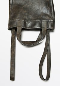 Svart läderväska med platt design, två korta handtag och en lång axelrem. Ytan är något sliten med en naturlig textur.