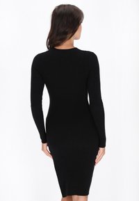 Abito a costine nero con maniche lunghe, silhouette aderente e orlo al ginocchio. Tessuto morbido e leggermente elasticizzato per il comfort.
