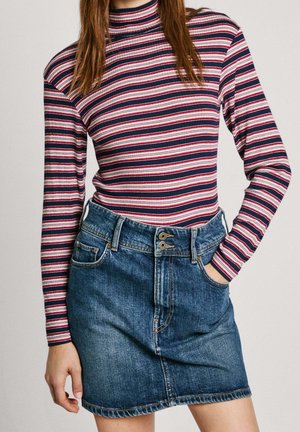 Gestreepte coltrui met lange mouwen in marineblauw, rood en wit; gecombineerd met een hooggetailleerde denim rok met knopen aan de voorkant en zakken.