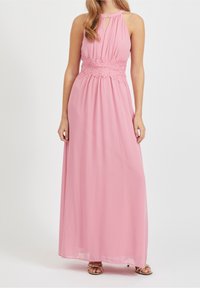 Robe maxi rose avec un col licou, présentant un détail en crochet à la taille, un tissu en chiffon fluide, et une ouverture en forme de goutte d'eau au niveau du décolleté.