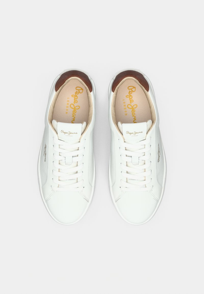 Baskets blanches en cuir avec une texture lisse, présentant des orteils ronds, des lacets plats et un accent en cuir marron autour du col. Marquage doré visible.