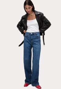 Blå jeans med vida ben och hög midja, kombinerade med en vit linne och en svart läderjacka, med en slät textur och fem fickor.