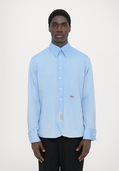 Lichtblauw langemouwen shirt, met knoopsluiting, zachte textuur, voorzien van een klein rood logo en label op de zoom, met een standaard kraag.