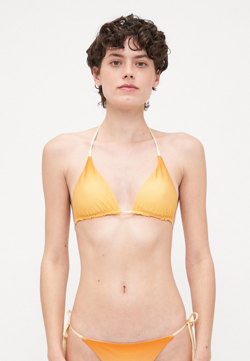 Trīsstūra bikini, kas izgatavots no gludas oranžas auduma ar krēmkrāsas auklām, ar savilkta mala un sānu auklas aizdari apakšdaļai.