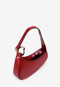 Bolso de mano de cuero rojo con forma curva, que presenta un acento de hardware dorado y un ribete negro. Correa individual para el hombro y cierre con cremallera.