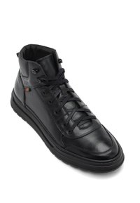 Zapatillas altas de cuero negro con una superficie texturizada, punta redonda, cordones planos y ojales de metal. Suela de goma lisa y cuello acolchado.