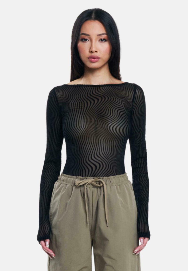 Top nero a maniche lunghe in mesh con un motivo ondulato. Il tessuto ha una texture trasparente con un collo rotondo, abbinato a pantaloni oliva con cordoncino.