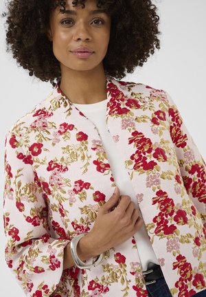 Kvetinové kimono v svetloružovej farbe s červenými a zlatými kvetinovými vzormi, širokými rukávmi a voľným strihom. Doplnčené strieborným náramkom.