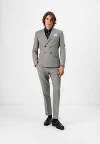 Ljusgrå dubbelknäppt kostym med slagkrage, matchande slim-fit byxor och en mörk skjorta. Inkluderar en vit näsduk och svarta loafers.