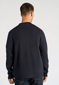 Granatowy prążkowany sweter z okrągłym dekoltem, długimi rękawami i luźnym krojem; wykonany z teksturowanej tkaniny o minimalistycznym designie.