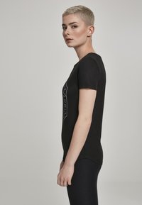 Sort bomuld T-shirt med korte ærmer, tætsiddende pasform, prydet med en geometrisk hvid grafik på forsiden, glat tekstur og rund halsudskæring.