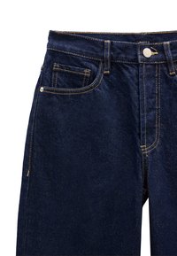 Granatowe dżinsy z żółtym przeszyciem. Posiadają przednią kieszeń, guzik w pasie oraz suwak. Klasyczny krój prosty.