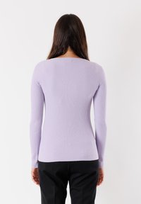 Top lungo a maniche con costine di color lilla, dal design aderente e scollo a barca. Il tessuto sembra morbido, elastico e leggero per garantire comfort.