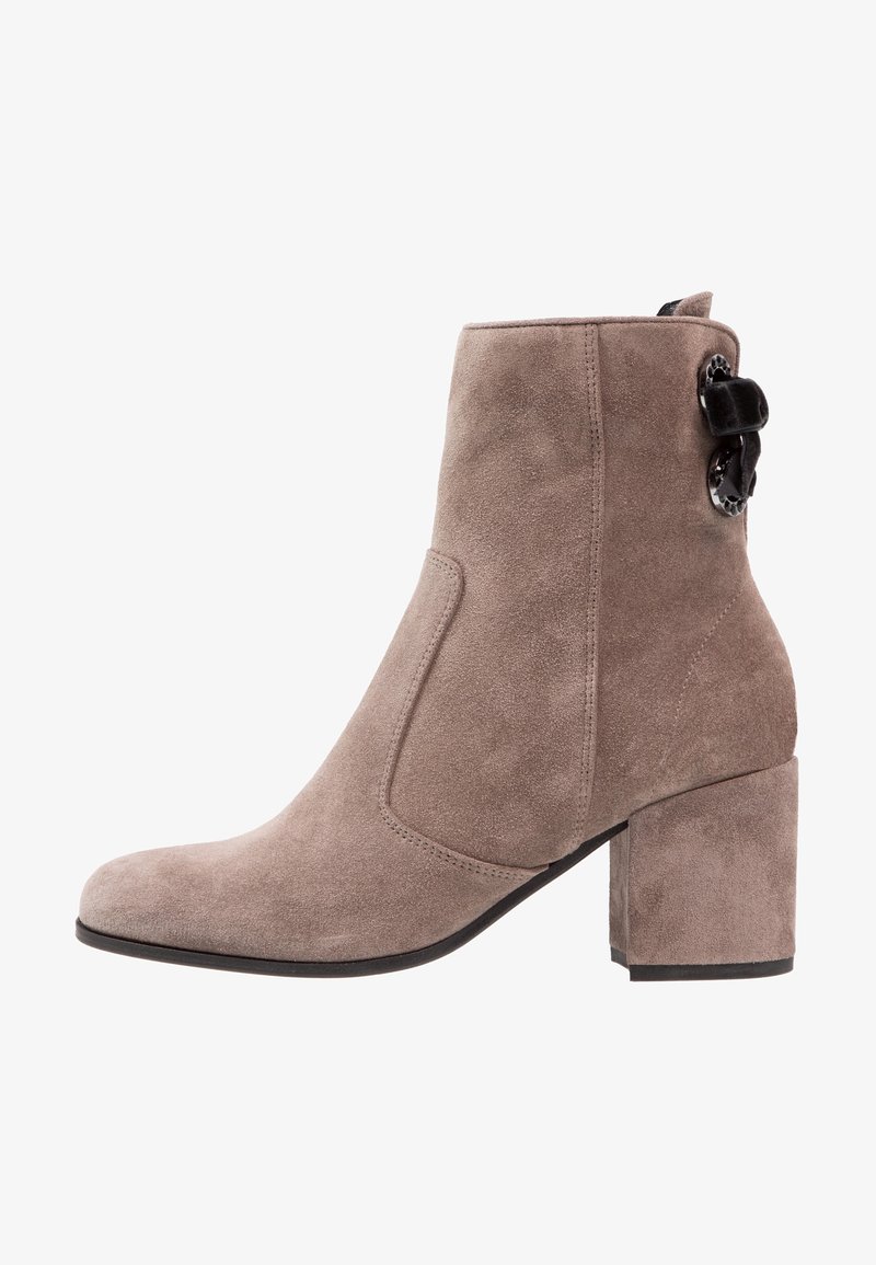 Bottine en daim taupe avec talon bloc et boucle décorative noire sur le côté, vue de profil intérieur.