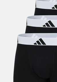 Svart herrunderklädesset med vit elastisk midja med svart trestripeslogotyp och slät tygtextur.