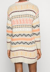 Maglione lavorato a maglia con base color crema, caratterizzato da motivi geometrici multicolori in rosa, arancione, nero e bianco. Maniche lunghe e orlo a coste.