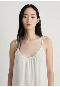 Hvid camisole med tynde stropper, der har en afslappet pasform og samlet halsudskæring. Fremstillet af letvægtsstof med en glat overflade.