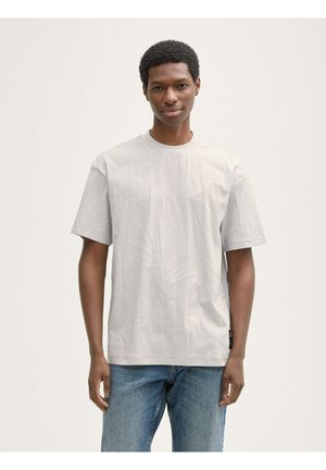 Lichtgrijs T-shirt met korte mouwen met een subtiel bladerenpatroon, ronde halslijn en een losse pasvorm, gecombineerd met blauwe denim jeans.
