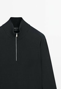 Pullover nero a maglia con colletto alto e chiusura con zip corta. Presenta polsini e orlo a costine, texture liscia e design minimalista.