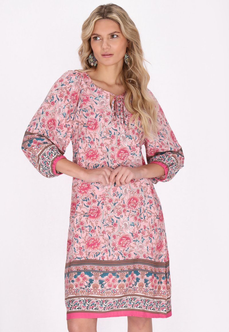 Rochie cu imprimeu floral în nuanțe de roz, cu accente albastre și verzi. Are mâneci trei sferturi, gât legat și margini decorative cu model.