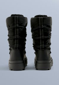 Czarne wodoodporne buty z wyściółką, elastycznym ściągaczem i teksturowanymi gumowymi podeszwami. Posiadają wzmocnioną piętę i detale w formie przeszyć.