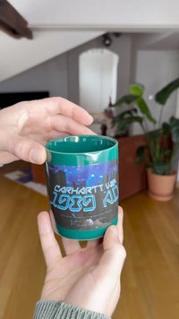 Roheline keraamiline kruus läikiva pinnaga, millel on sinine linnapilt ja julge tekst "Carhartt WIP 1989 A.D."