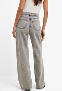 Gray wide-leg jeans with an elastic waistband, two back pockets, and a light, textured denim finish. Casual fit with a high-rise design.