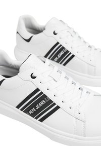 Bijele tenisice s glatkom kožnom površinom, crnim prugama i oznakom "PEPE JEANS LONDON". Imaju ravne bijele vezice i okrugli vrh.