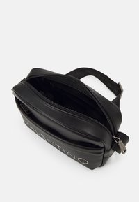 Black leather bag with a zip closure, featuring a smooth texture and prominent "VALENTINO" logo. Includes adjustable strap for versatility.