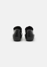 Schwarze Lackledersneaker mit niedrigem Profil, runder Zehenform und elastischen Öffnungen; Gummisohlen und strukturierte Akzente auf der Rückseite.