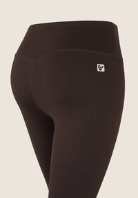 Leggings negros de cintura alta, con un pequeño logo y costuras planas visibles. Fabricados con una tela lisa y elástica.