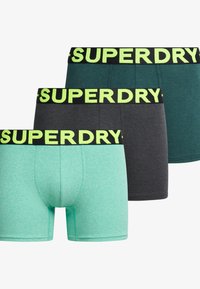 Tres pares de calzoncillos para hombres, con un diseño en verde menta, verde oscuro y gris oscuro. Cada uno tiene una cinturilla negra con el logo amarillo de "SUPERDRY".