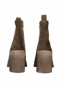 Brązowe zamszowe botki za kostkę z masywnym obcasem, tylnym zamkiem błyskawicznym i teksturowaną podeszwą. Posiadają lekko podniesioną krawędź na górze, co ułatwia zakładanie.